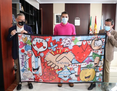 El artista Fernando Sembrador entrega a los dos alcaldes una bandera que simboliza la unión